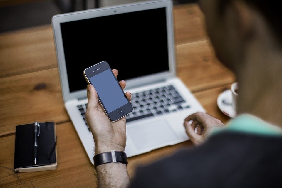 Person with a phone in hand with the computer open